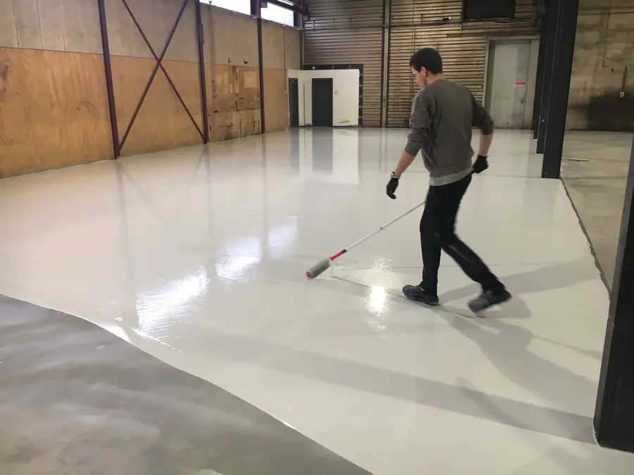 Epoxygulv rulles ud på betongulv i værksted