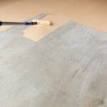Worker Painting Floor of Garage with Roller.