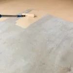 Worker Painting Floor of Garage with Roller.